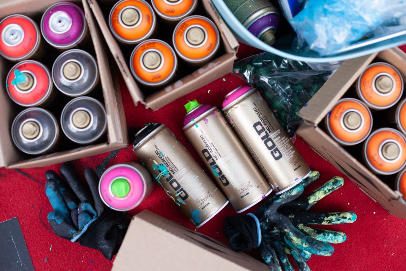 Spray paint cans with visible brand names on a red surface